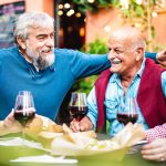 Genuine retired people having fun drinking red wine at dinner party